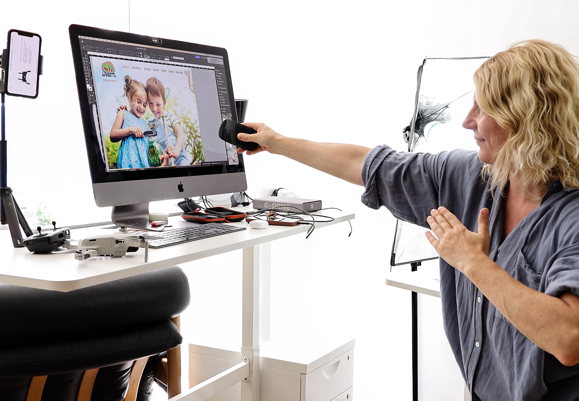 edelmarke-studios-jasmin-schoenitz-website-drohne Kreativdirektorin Jasmin Schönitz gestikuliert vor ihrem iMac, auf dem ein Webdesign-Entwurf mit Kinderfoto geöffnet ist – im Studio von Edelmarke Studios in Stralsund.